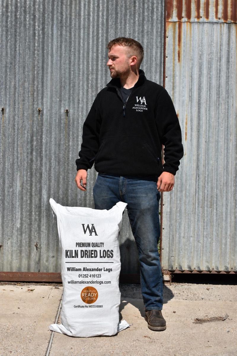 A member of the William Alexander team standing with an Easy Bag of kiln-dried logs at the yard